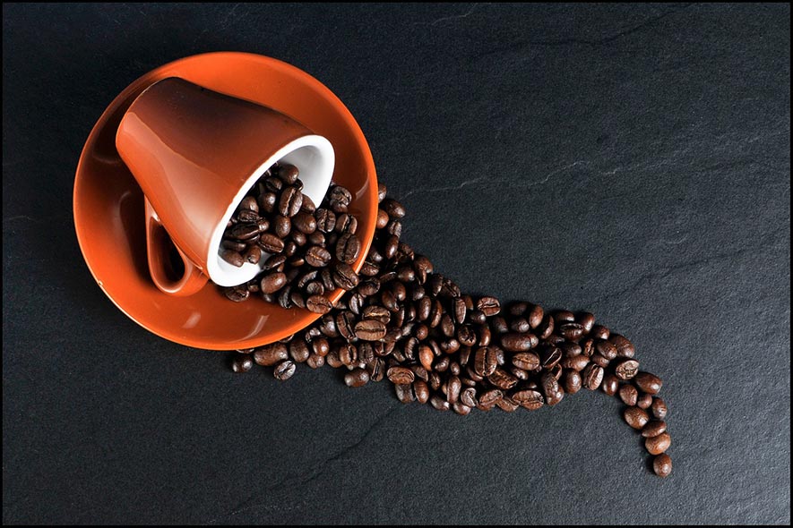 coffee cup and beans spilling out on to the table